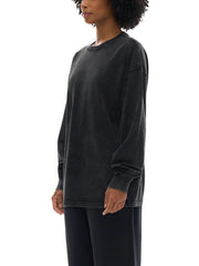 Woman wearing a loose, faded black long-sleeve crewneck shirt and black pants on white background
