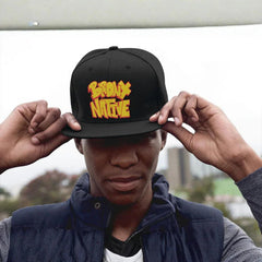 Black Bronx Native snapback hat with bold yellow-red embroidery, worn by man in urban setting